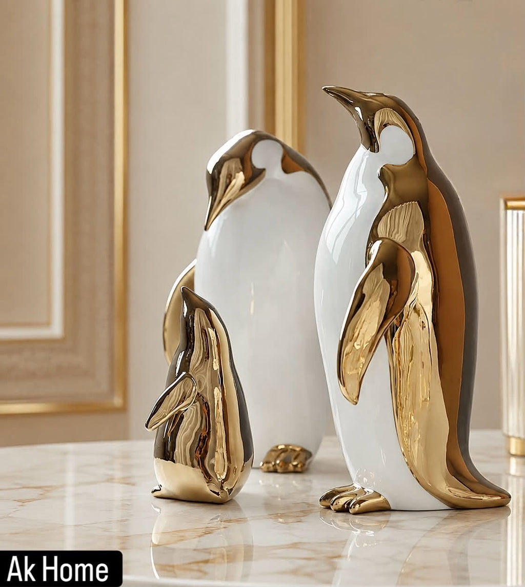 Gold & White Penguin Family Ceramic Sculptures Set of 3 – large, medium and small emperor penguin figurines in gold and white on marble surface