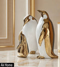 Gold & White Penguin Family Ceramic Sculptures Set of 3 – large, medium and small emperor penguin figurines in gold and white on marble surface